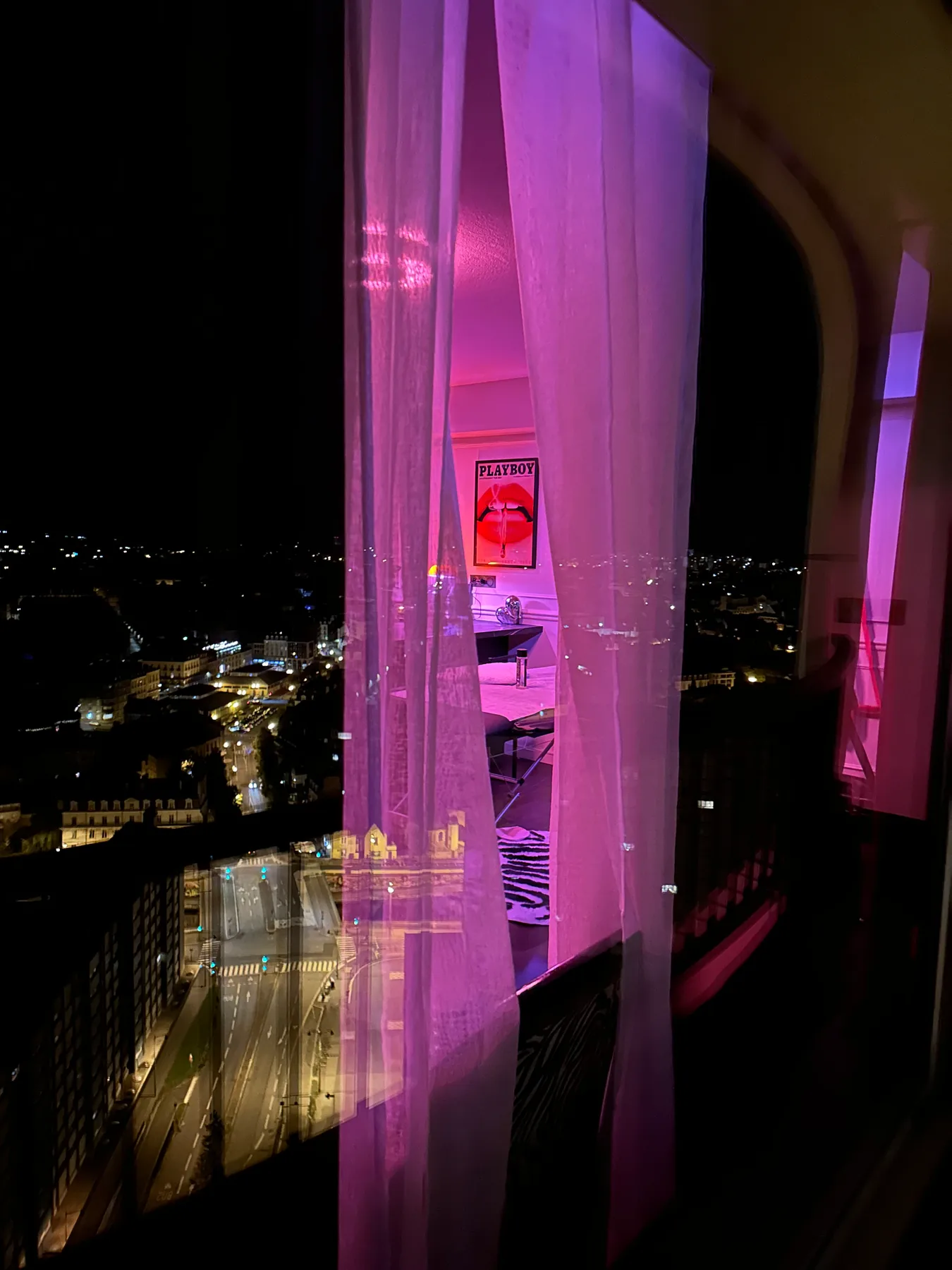 Rideaux éclairés en rose et vue sur Rennes la nuit